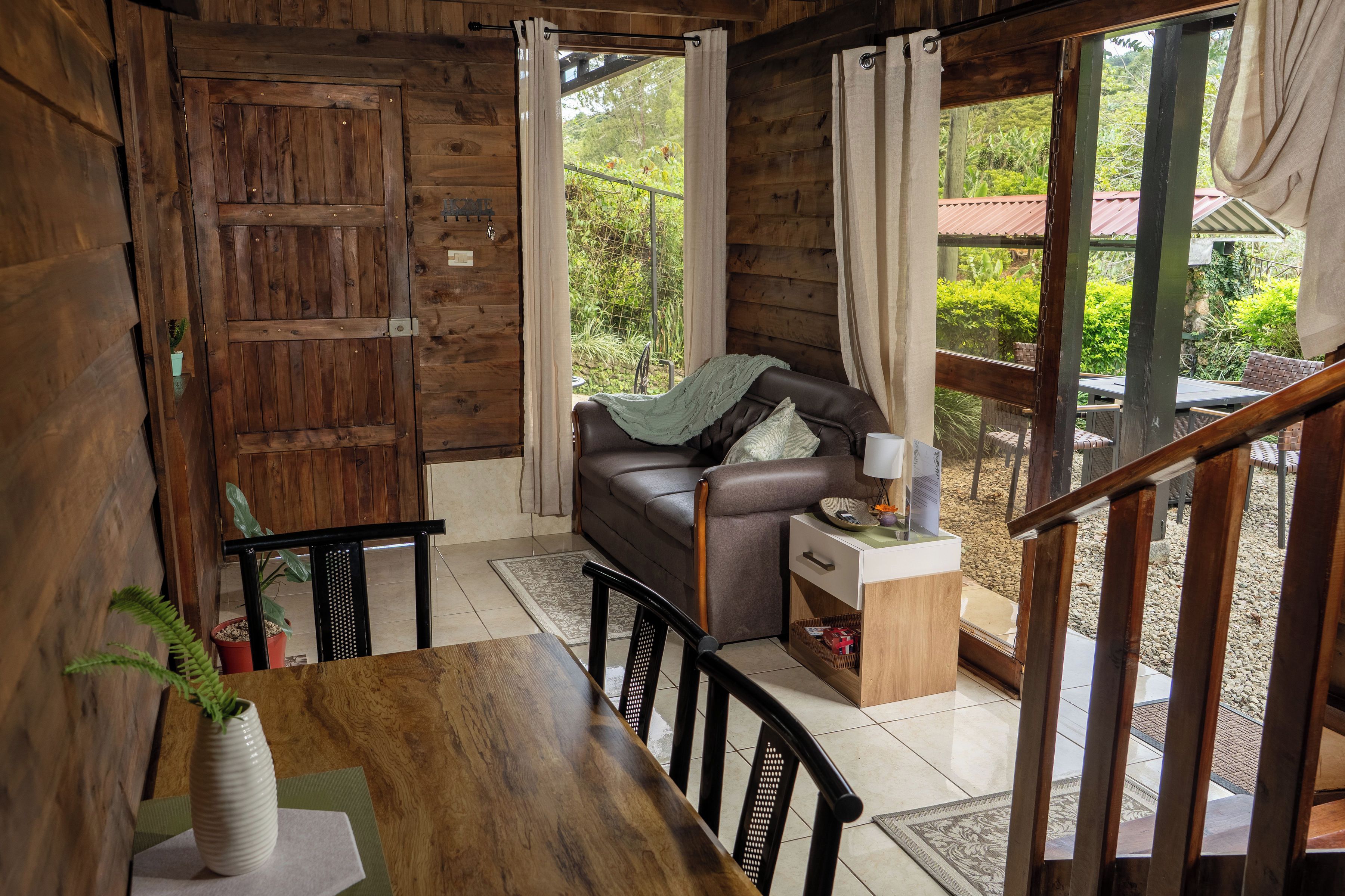 Un interior de madera con un sofá, una mesa de comedor y vistas al exterior.