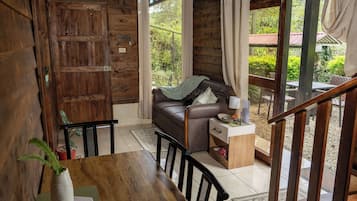 Un interior de madera con un sofá, una mesa de comedor y vistas al exterior.