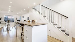 Una cocina moderna con encimera de madera, armarios blancos y campana extractora de acero inoxidable.