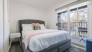 Un dormitorio con cama, mesita de noche y vistas al exterior.