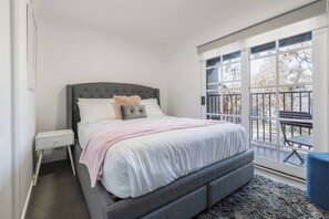 Ein Schlafzimmer mit Bett, Nachttisch und Blick ins Freie.