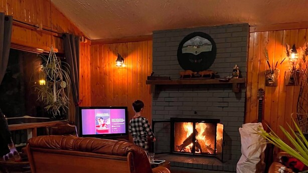 A cozy living room with a fireplace, leather sofa, and a television. - Chalet Du Nord (Saint-Adolphe-d'Howard)