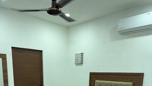 A bedroom with a bed, a ceiling fan, a door, and an air conditioning unit.