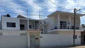 A two-story building with a white exterior, a garage, and a balcony with a metal railing.