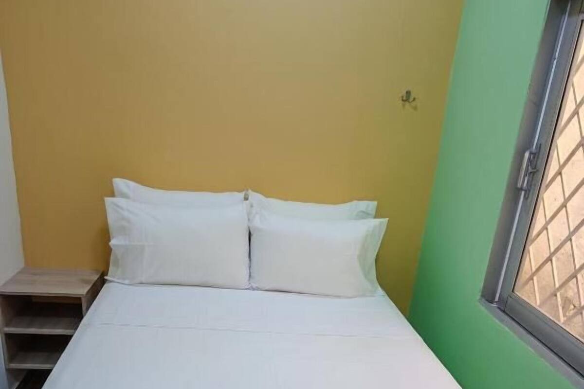 A single bed with white bedding in a room with yellow and green walls.