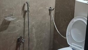Une salle de bain équipée de toilettes, d’une douche et d’un chauffe-eau rose.