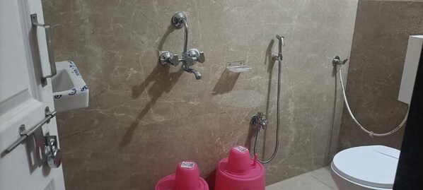 A bathroom with a shower, toilet, and a sink with a soap dispenser. - Maharaja guest house nashikkar (Akalkot)