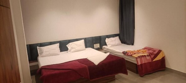 Une chambre avec deux lits, une tête de lit sombre et une fenêtre avec un rideau.