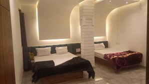 Une chambre avec deux lits, un pilier blanc et un mur aux lignes courbes.