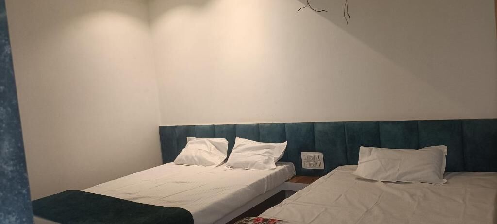 Quarto com duas camas de solteiro, cada uma com roupa de cama branca e cabeceira azul.