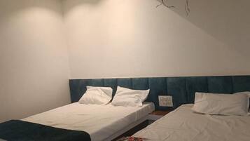 Quarto com duas camas de solteiro, cada uma com roupa de cama branca e cabeceira azul.