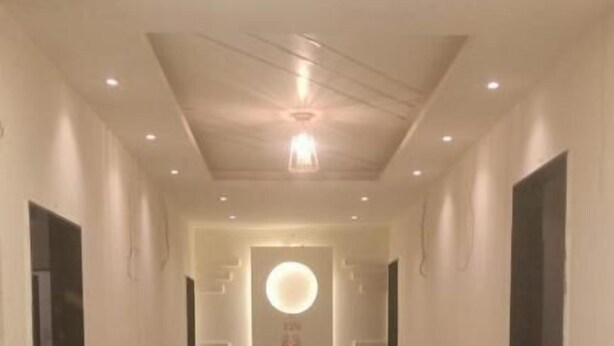 Un couloir doté d’un plancher poli, d’un éclairage encastré et d’un luminaire circulaire central.