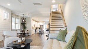 Ein geräumiges Wohnzimmer mit einer Couch, einem Essbereich und einer Küche im Hintergrund.