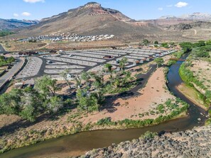Un vaste espace de stationnement comprenant de nombreuses rangées de places, une rivière et une chaîne de montagnes en arrière-plan.