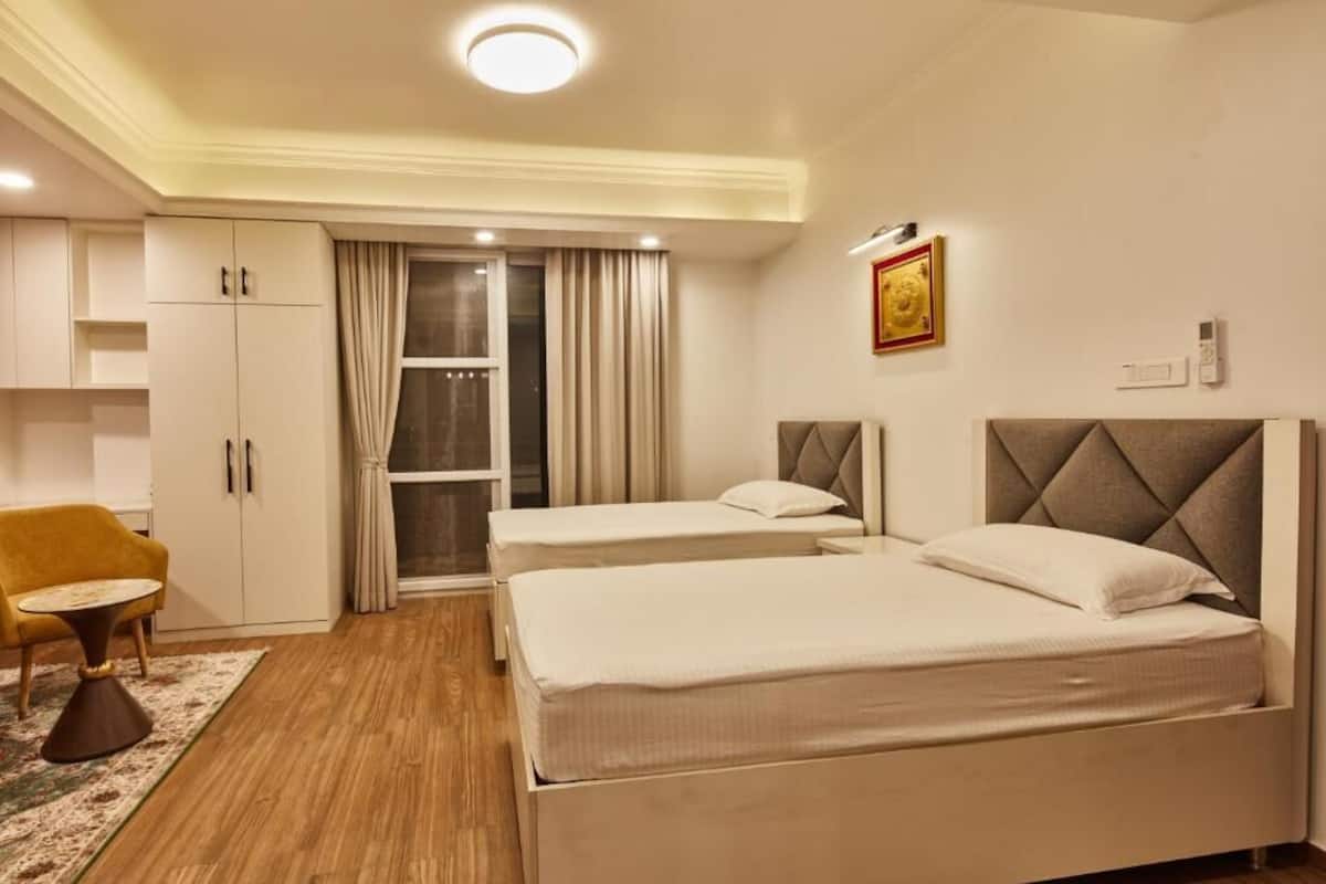 A hotel room with two beds, a sofa, a small table, and a wardrobe.