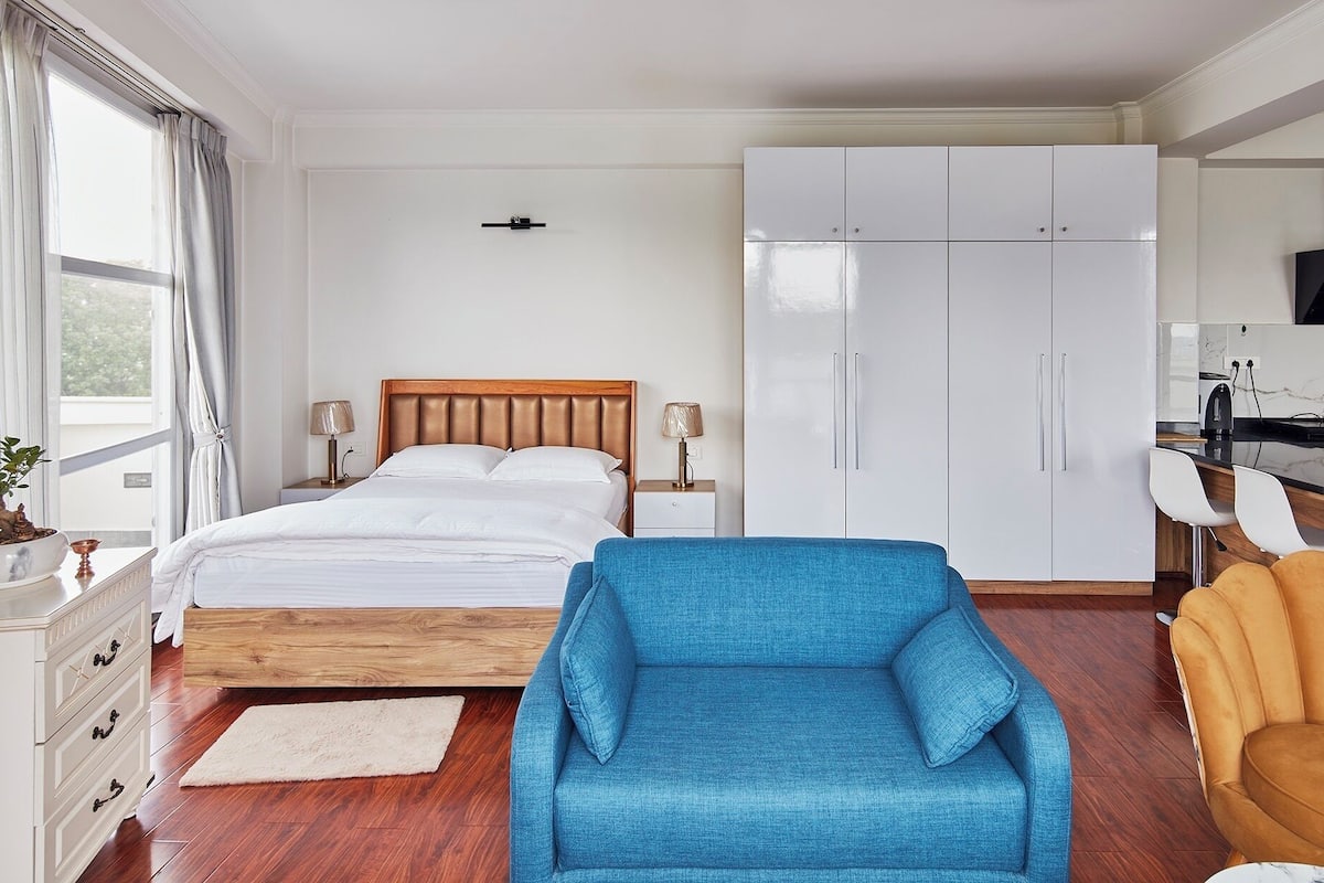 A bedroom with a bed, a wardrobe, a desk, and a chair.
