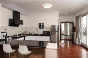 A modern kitchen with a black countertop, white cabinets, a stainless steel refrigerator, and a built-in microwave. - Luminous Apartments & Suites (Kathmandu)