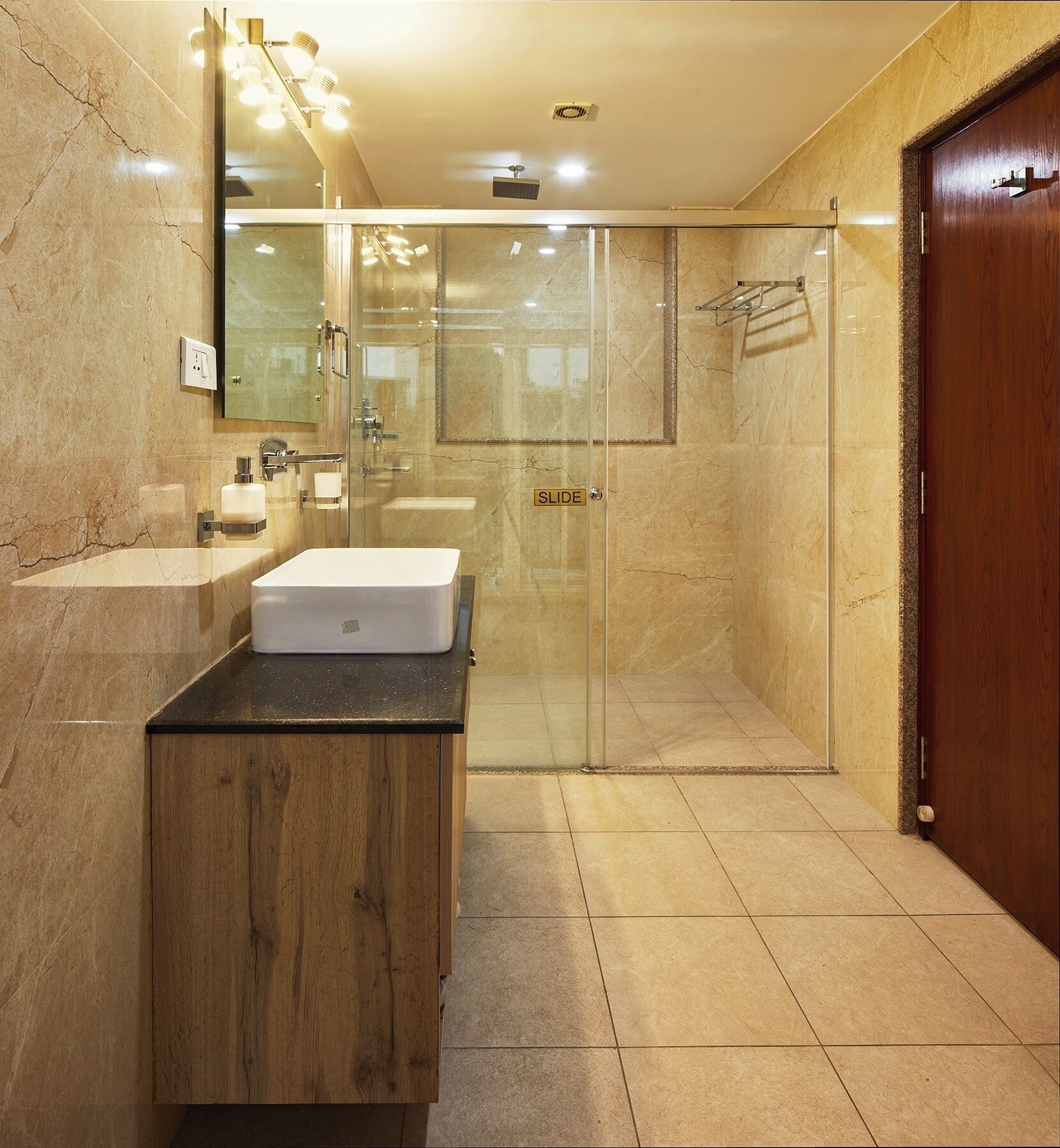 A modern bathroom with a glass shower enclosure, a wooden vanity, and a large mirror.