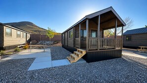 Une cabane dotée d’une terrasse en bois, d’un escalier et d’un sol en gravier.
