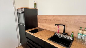 Une cuisine compacte dotée d’un four encastré, d’un évier et d’un plan de travail en bois.