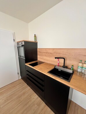 A compact kitchen with a built-in oven, a sink, and a wooden countertop. - Forest & Wind - Nature Meets Modernity (Marburg)