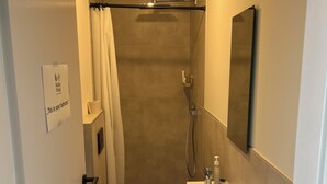 Une petite salle de bain comprenant une douche, des toilettes et un lavabo.