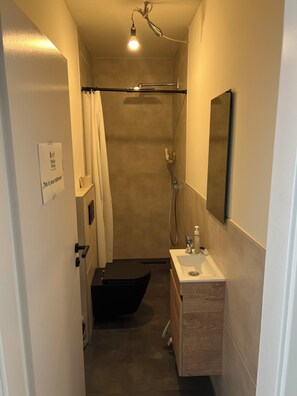 A narrow bathroom with a shower, toilet, and sink. - Forest & Wind - Nature Meets Modernity (Marburg)