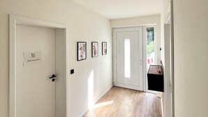 Un couloir doté d’un plancher en bois, de murs blancs et d’un luminaire au plafond.