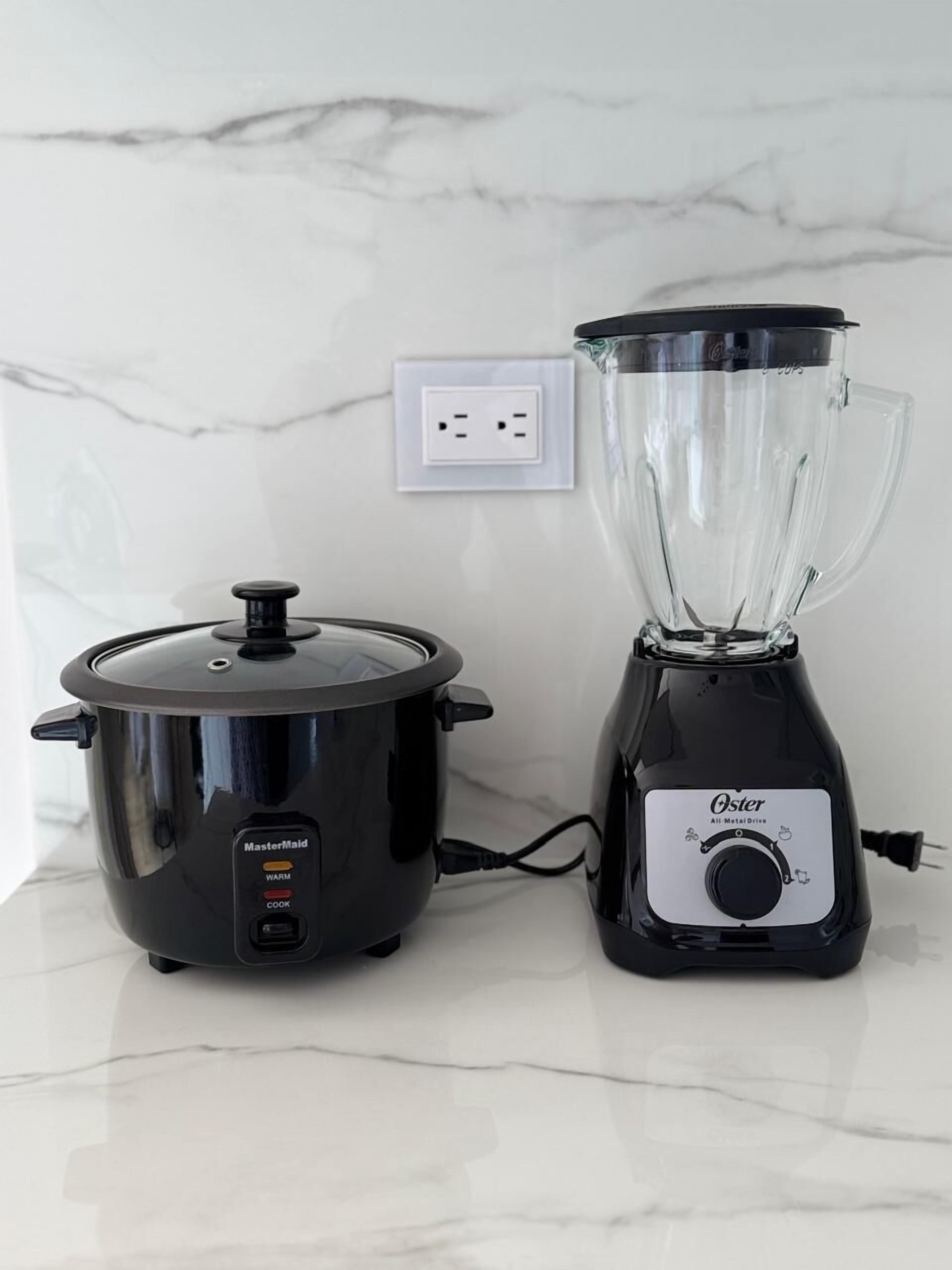 A MasterMaid slow cooker and an Oster blender on a marble countertop.