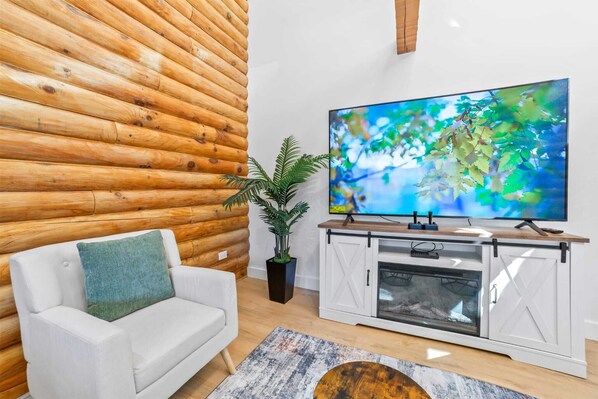 Ein Wohnzimmer mit einem weißen Sofa, einem Flachbildfernseher, einem Kamin und einer Holzwand.