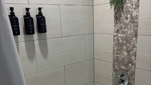 A bathroom with a bathtub, a wall-mounted plant, and three black bottles labeled 'BODY WASH,' 'SHAMPOO,' and 'CONDITIONER.' - Welcome to your home away from home. A calm, escape designed for pure relaxation (Decatur)