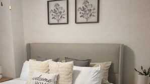 A bedroom with a bed, pillows, a bedside table, a lamp, and two framed floral artworks on the wall. - Welcome to your home away from home. A calm, escape designed for pure relaxation (Decatur)