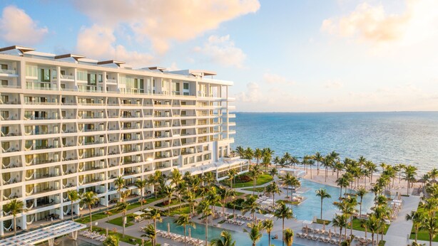 A high-rise hotel with multiple balconies, a pool area with sun loungers, and a view of the ocean. - Cozy 2-bedroom condo with AC in perfect Cancún location (Cancún)