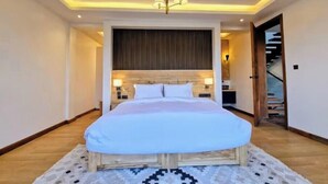 Una camera da letto con un letto, una testiera in legno, un tappeto decorato e una scala sullo sfondo.
