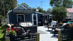 Une petite maison avec une terrasse, du mobilier d’extérieur et une antenne parabolique.