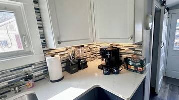A kitchen with white cabinets, a countertop, a sink, a window, and a door.