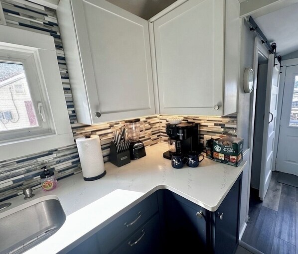A kitchen with white cabinets, a countertop, a sink, a window, and a door.