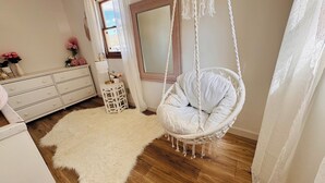 Une pièce avec un fauteuil suspendu, une commode, un miroir et un tapis moelleux.