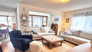 Un salon avec un fauteuil bleu foncé, un canapé beige, une table basse en bois et un tapis.