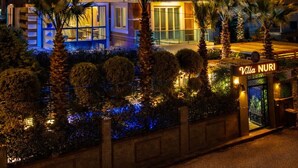 A modern Villa Nuri hotel with a prominent sign, large windows, and palm trees. - Villa Nuri Konaklama (Antakya)