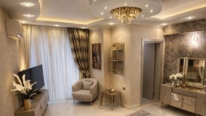 A spacious living room with a chandelier, a flat-screen TV, and a large sofa. - Villa Nuri Konaklama (Antakya)