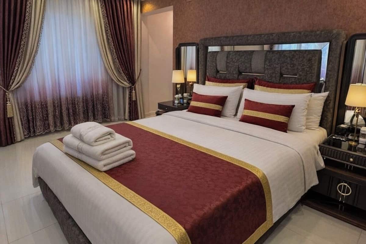 Une chambre d’hôtel moderne équipée d’un grand lit, d’une table de chevet, d’un climatiseur et d’un miroir.