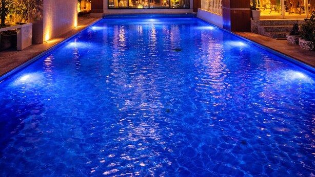 A modern hotel with a swimming pool, large windows, and a well-lit interior. - Villa Nuri Konaklama (Antakya)