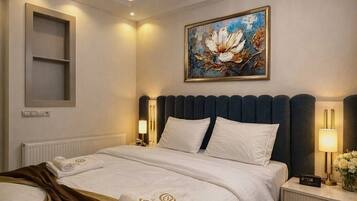 A modern hotel room with a large bed, a painting on the wall, a chandelier, and a bedside table with a lamp.