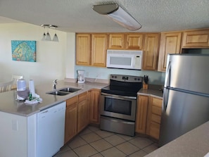 A kitchen with wooden cabinets, a stainless steel refrigerator, a microwave, a dishwasher, and a coffee maker. - Sands Villa Resort Oceanfront Condo - 7 Night Discount July 4th - July 11th! (Atlantic Beach)