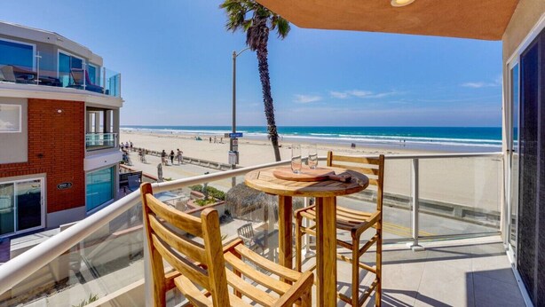 A balcony with a table and chairs overlooking a beach. - *New* Ocean Surf View | 2nd Floor Condo w/ Parking (San Diego)