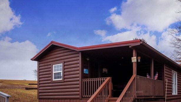 Eine Blockhütte mit Veranda, Holztreppe und kleinem Fenster.