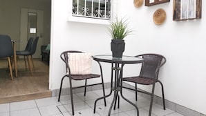 Eine Terrassenfläche mit zwei Korbstühlen, einem kleinen runden Tisch und einem Blumentopf.