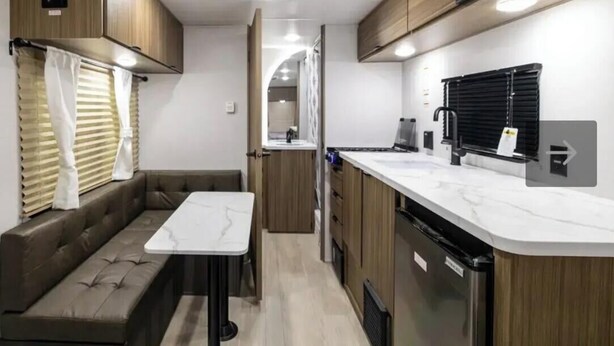 A compact RV kitchen with a dining area, built-in cabinets, and a countertop. - New Northwoods Escape!  2026 Wildwood FSX Camper Near Bike Trails, Lakes & Pines (Boulder Junction)