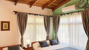 A hotel room with two beds, a ceiling fan, an air conditioning unit, and a framed picture on the wall. - Villa Tortuga Nosara (Playa Guiones)